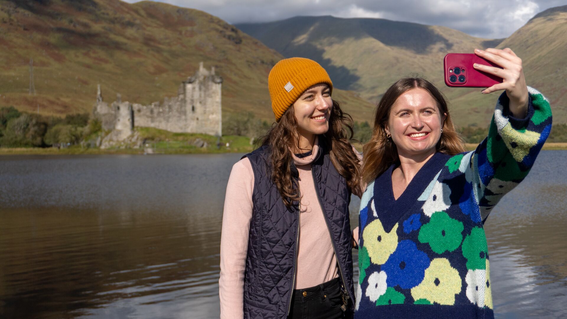 Two young female travellers takign a selfie before Kilchurn Castle