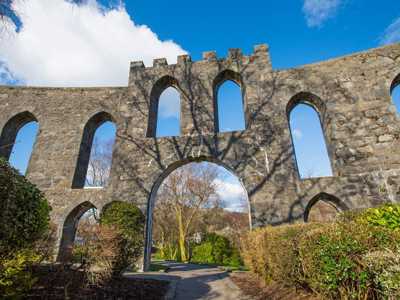 Close up view of MacCaigs Tower in Oban, an arched stone monument surrounded by trees