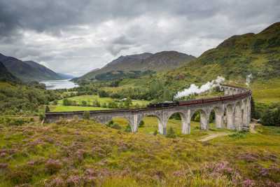 Jacobite Steam Train crossing Glenfinnan Viaduct, surrounded by scenic Highlands