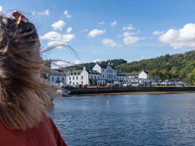 Female traveller enjoying views of Inveraray from the town's pier on a sunny day