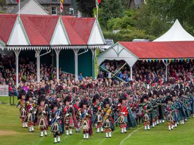 Large group of Scottish bagpipers playing opening music for the Braemar Gathering