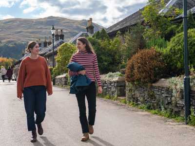 Two female travellers takign a relaxed walk through the traditional conservation village of Luss