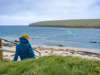Woman overlooking waterpassage to Brough of Birsay on Orkney