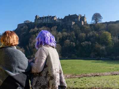 Two travellers admiring Stirlign Castle atop a hill from afar