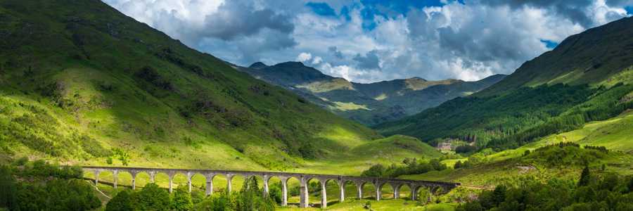 The iconic Glenfinnan Viaduct on a sunny day in summer with HIghland hills in the background