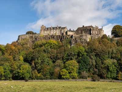 Stirling Castle from afar, sitting on a volcanic rock against blue skies