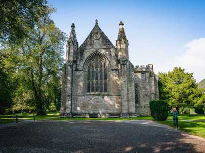 Stone-wall cathedral with large celtic-style windows surrounded by trees