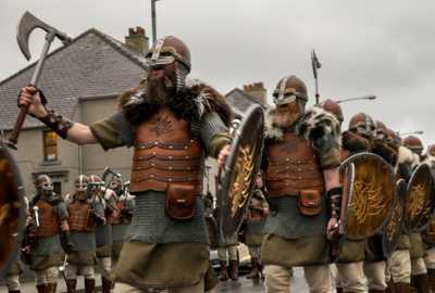 Up Helly Aa Viking parade with men in detailed Viking costumes, wearing helmets and cloaks, carrying axes
