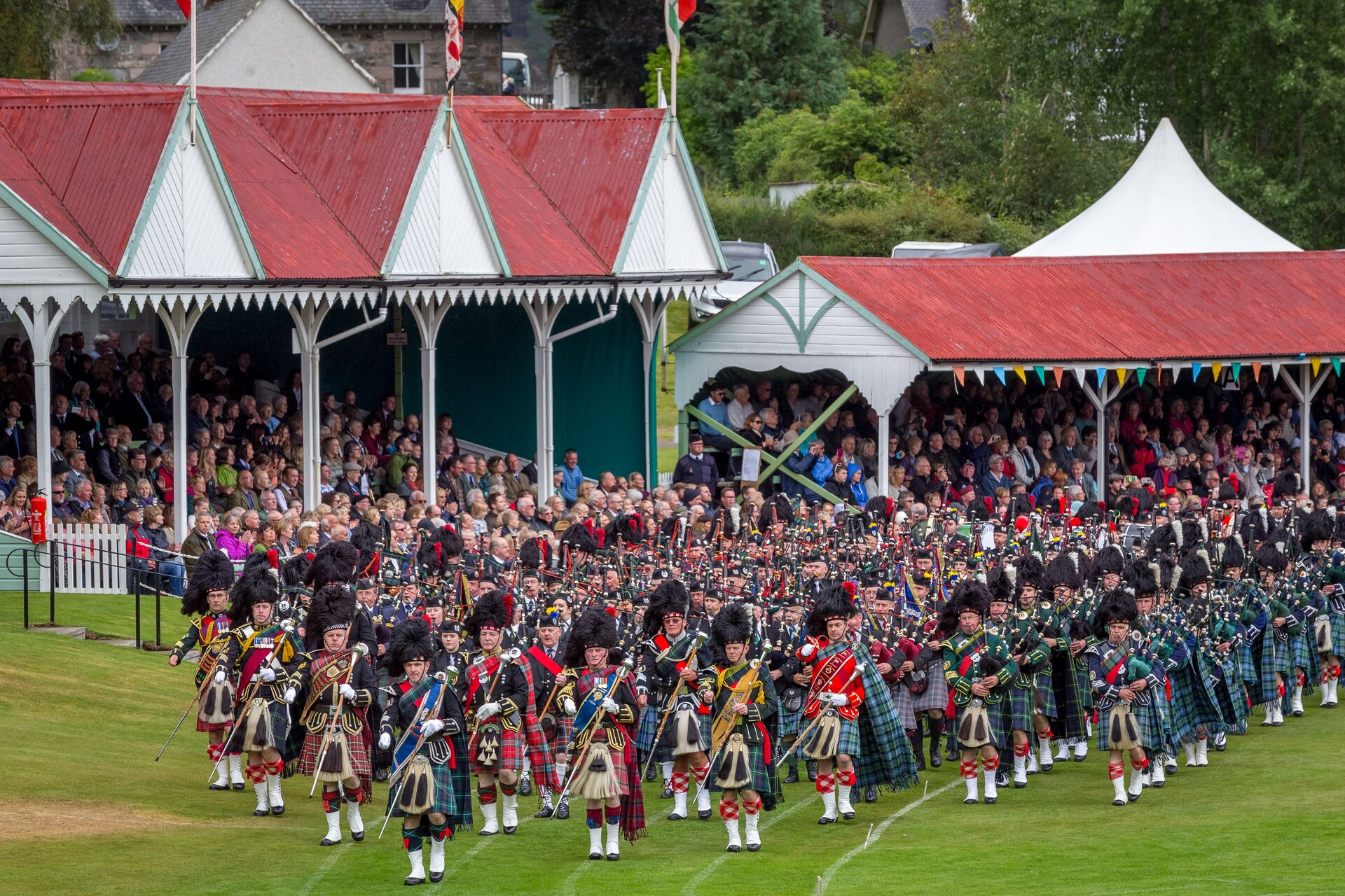 Large group of Scottish bagpipers playing opening music for the Braemar Gathering