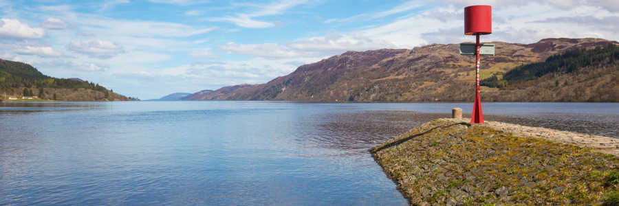 Viewing platform by the shores of Loch Ness with blue skies and hills in the background